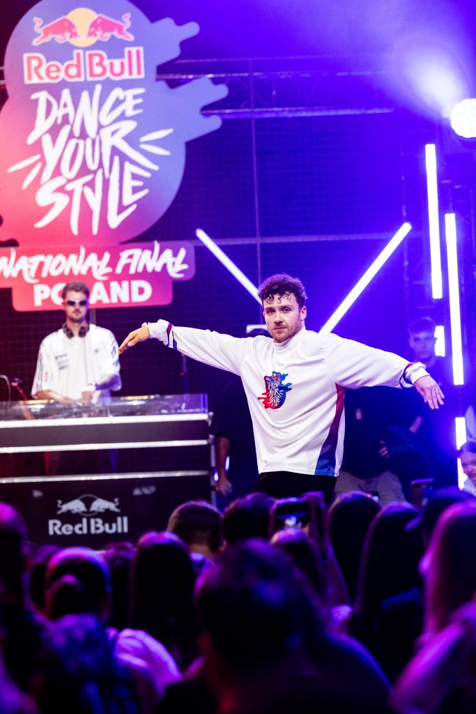 Tancerz podczas finału Red Bull Dance Your Style Poland na scenie z oświetleniem i publicznością.