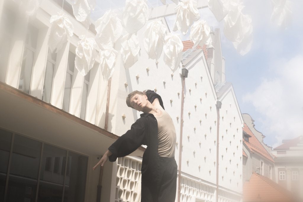 Contemporary w Poznaniu – tancerz Studio Nieznane wykonuje ekspresyjny ruch pod jasną instalacją artystyczną w centrum miasta